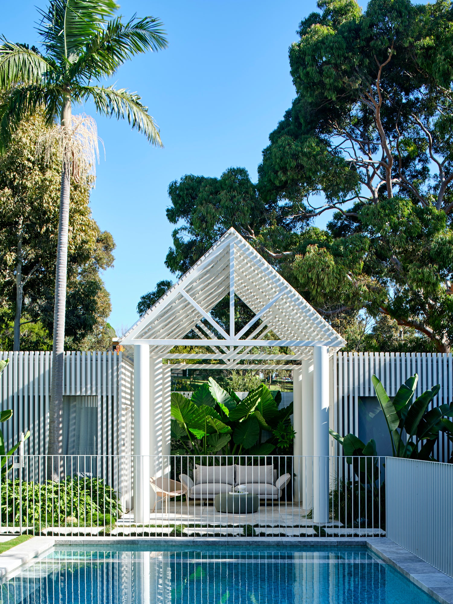 MALVERN PROJECT: A swimming pool with a wooden deck and a white pergola.